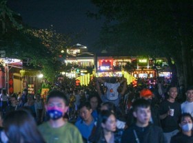 Image: Tourists walk around Hoi An ancient town, waiting in long queues to drop flower lanterns on the Tet holiday