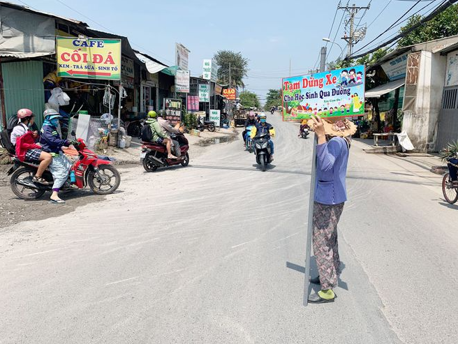 62 year old lady holds traffic sign to help students pass the road in Ho Chi Minh city video