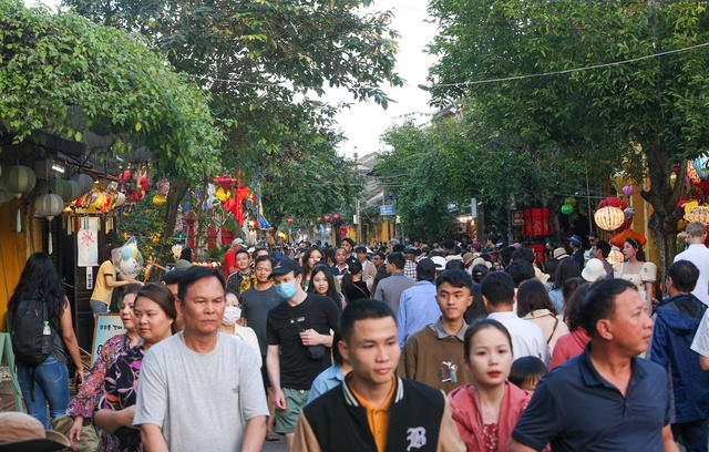 Tourists walk around Hoi An ancient town, waiting in long queues to drop flower lanterns on the Tet holiday